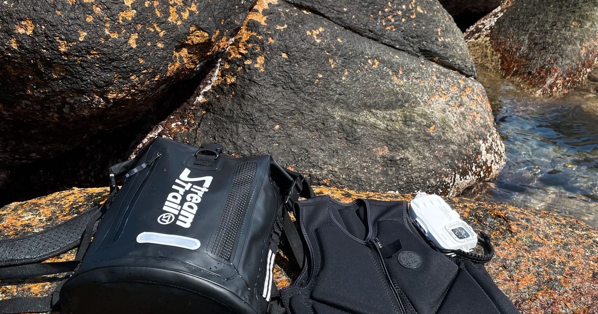 Diving equipment set on rocky seashore under bright blue sky.