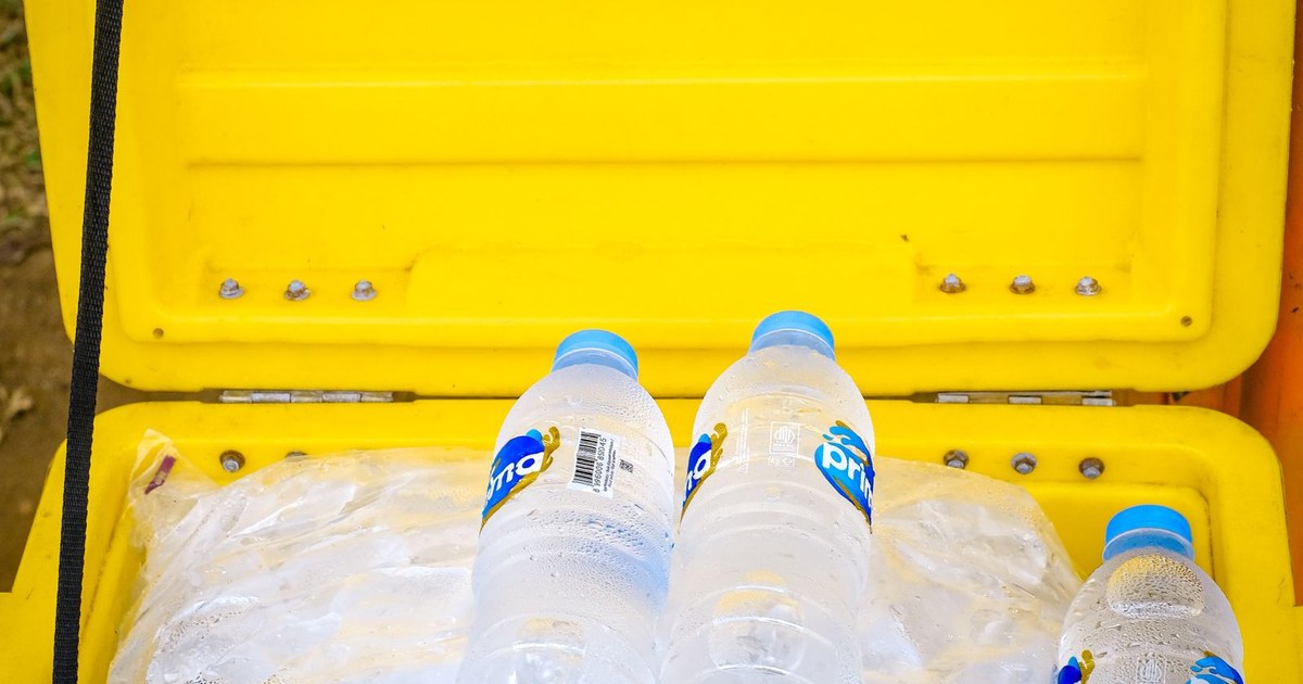 Bottled water in a yellow cooler with ice, perfect for outdoor summer hydration.