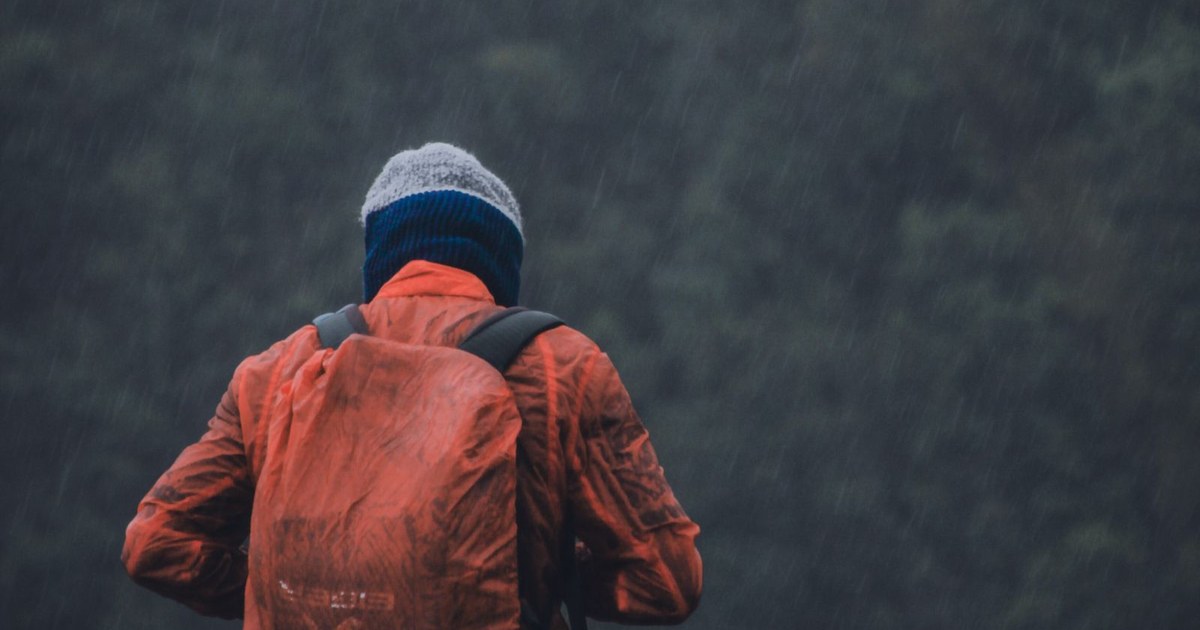 A solitary backpacker in colorful gear explores the misty highlands of Papua, Indonesia.