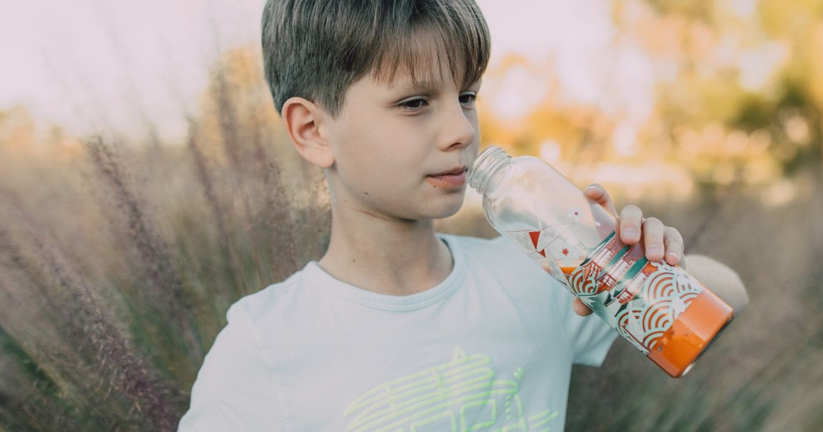 Boy drinking from a portable bottle outdoors