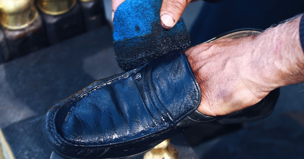Close-up of a person polishing a leather shoe using a brush, showcasing craftsmanship and care.