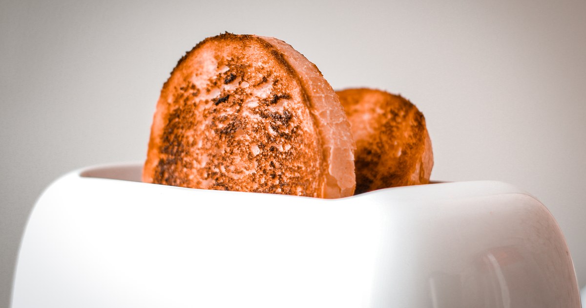 Golden brown slices of bread popping out of a white toaster, ready to serve.