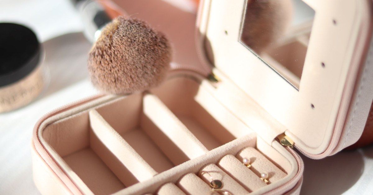 A luxurious jewelry box with earrings and a makeup brush bathed in gentle sunlight.