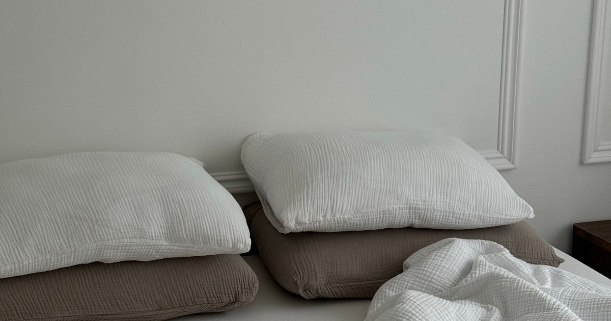 A cozy, minimalist bedroom featuring soft pillows and a white bedspread.