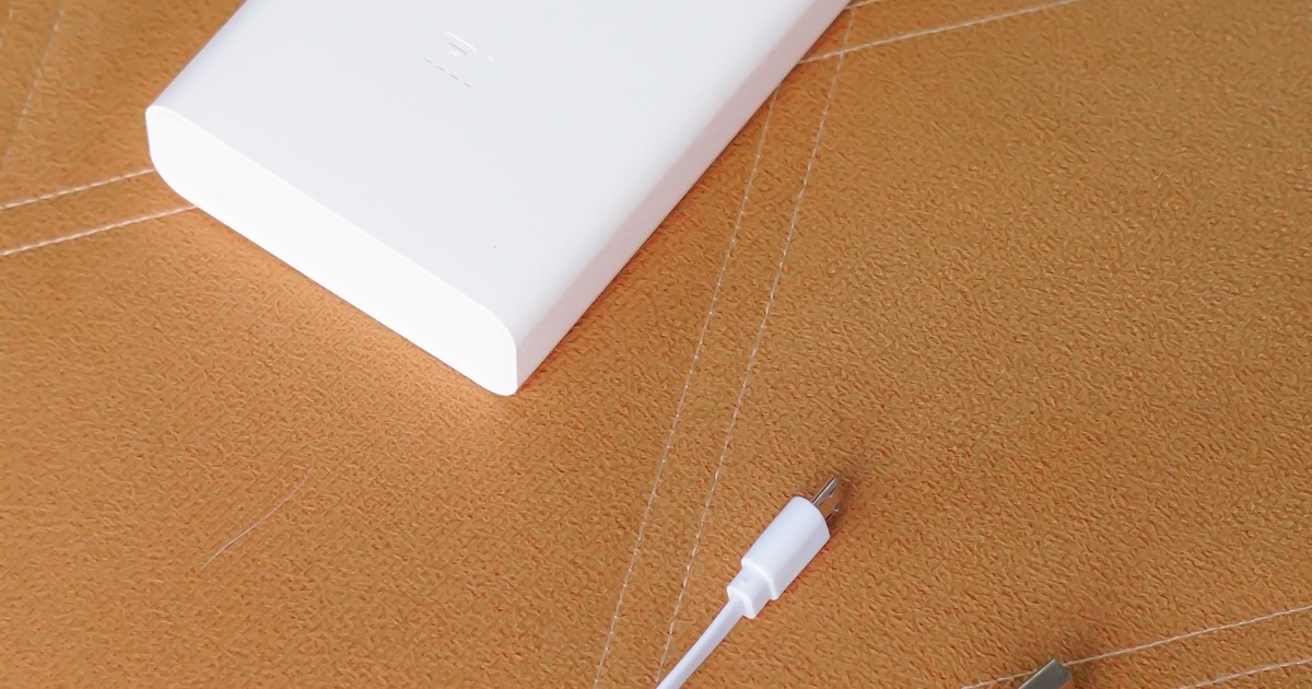 White power bank and charging cable on a textured brown surface, perfect for technology themes.