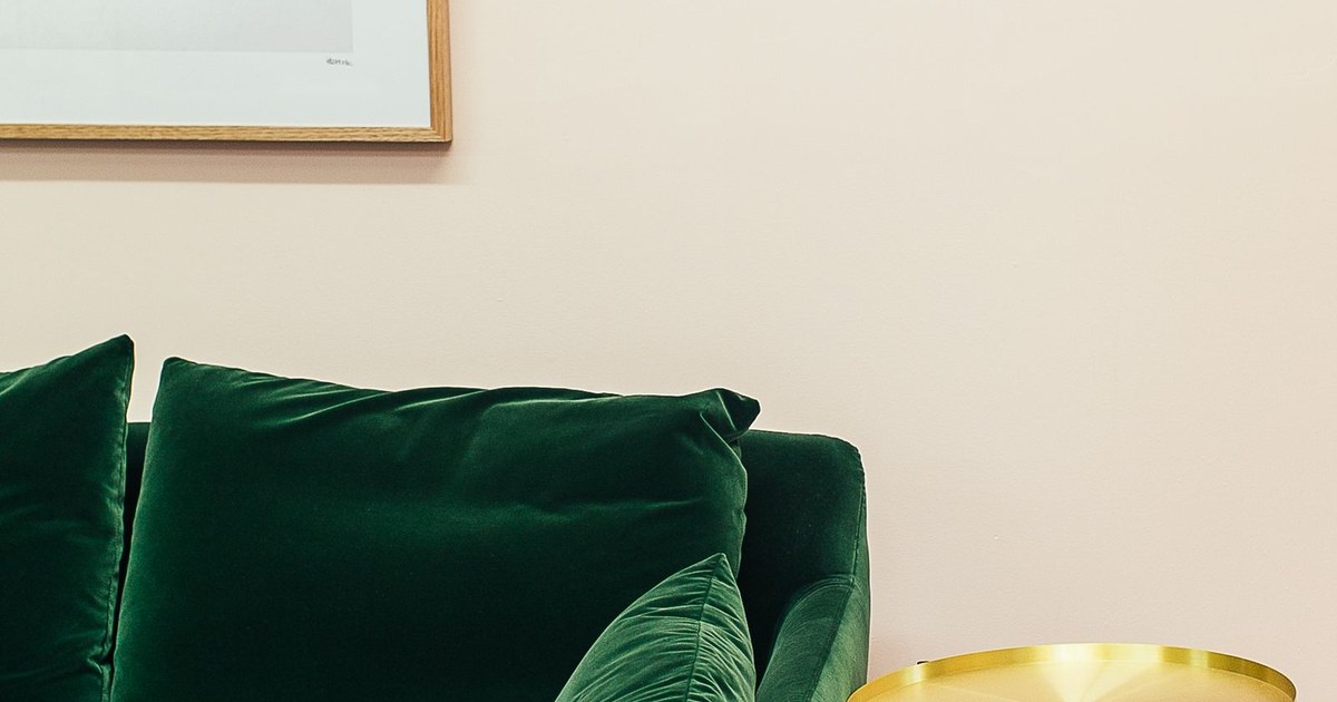 Soft comfortable green velour couch with cushions placed near small round table in stylish living room