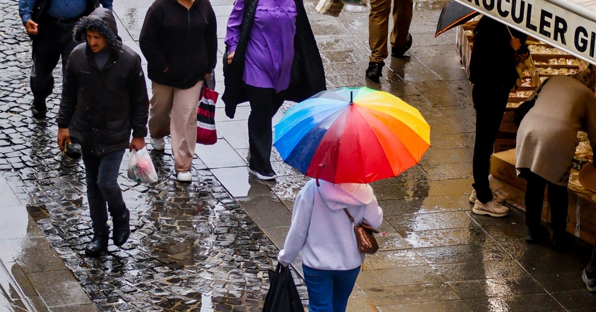 A colorful umbrella brightens a damp street market scene.