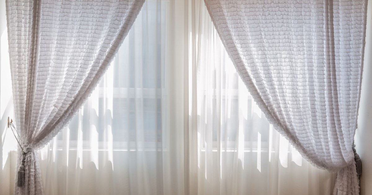 Sun shining through elegant white curtains in a cozy, modern interior setting.