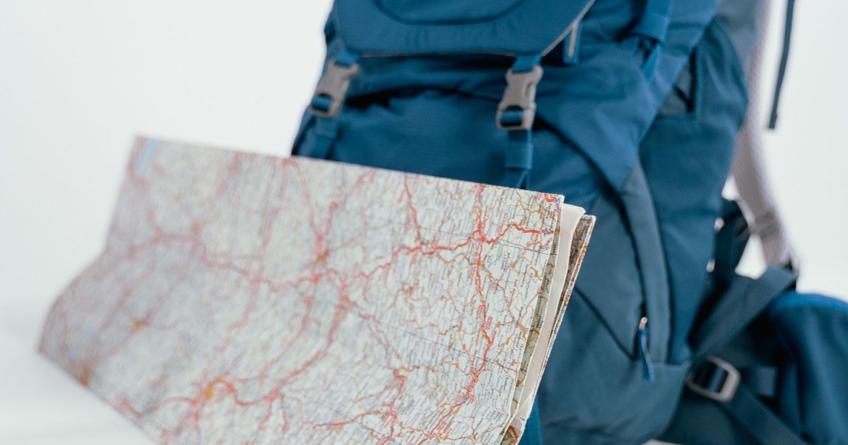 A blue backpack and map set up for hiking and travel adventures, emphasizing the spirit of exploration.