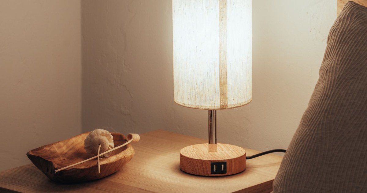 A warm and inviting bedroom scene with a glowing lamp on a wooden nightstand.