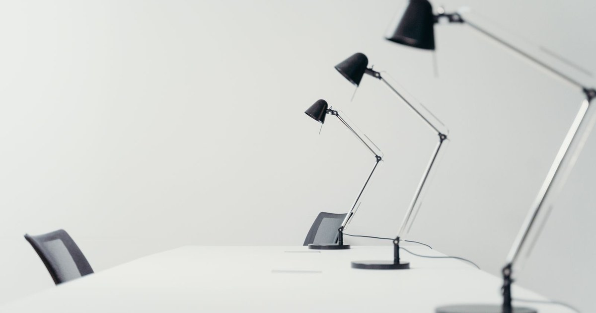 Sleek white office setting with modern black desk lamps and chairs, showcasing minimalism.