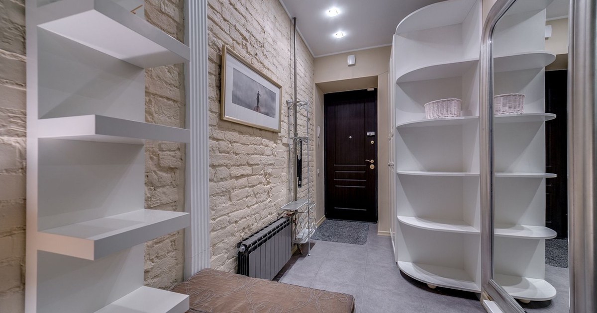 Contemporary entryway with sleek white shelving and neutral tones, featuring a comfortable bench.