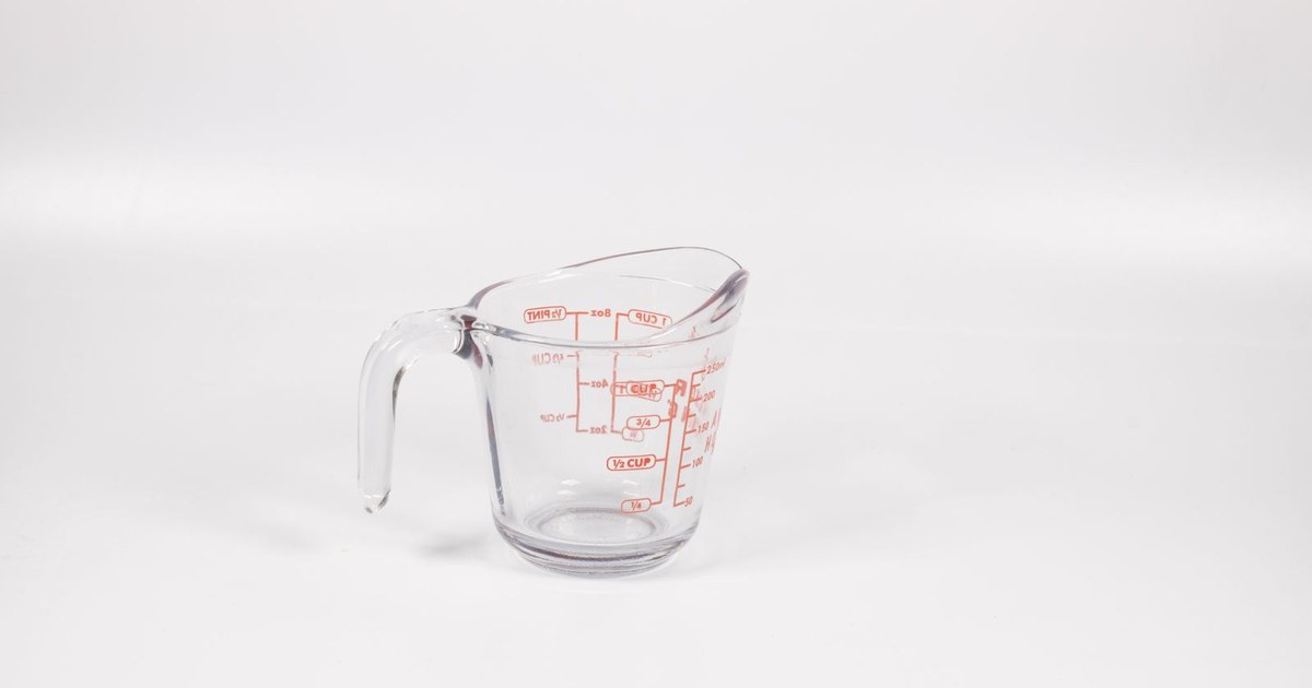 A clear glass measuring cup with red markings on a white background, perfect for culinary use.