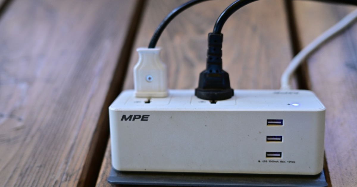 A power strip with multiple USB ports and cables connected on wooden surface.