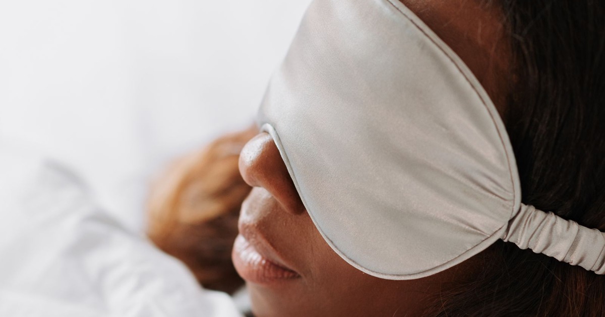 Woman resting peacefully in bed with an eye mask, capturing a serene morning moment.